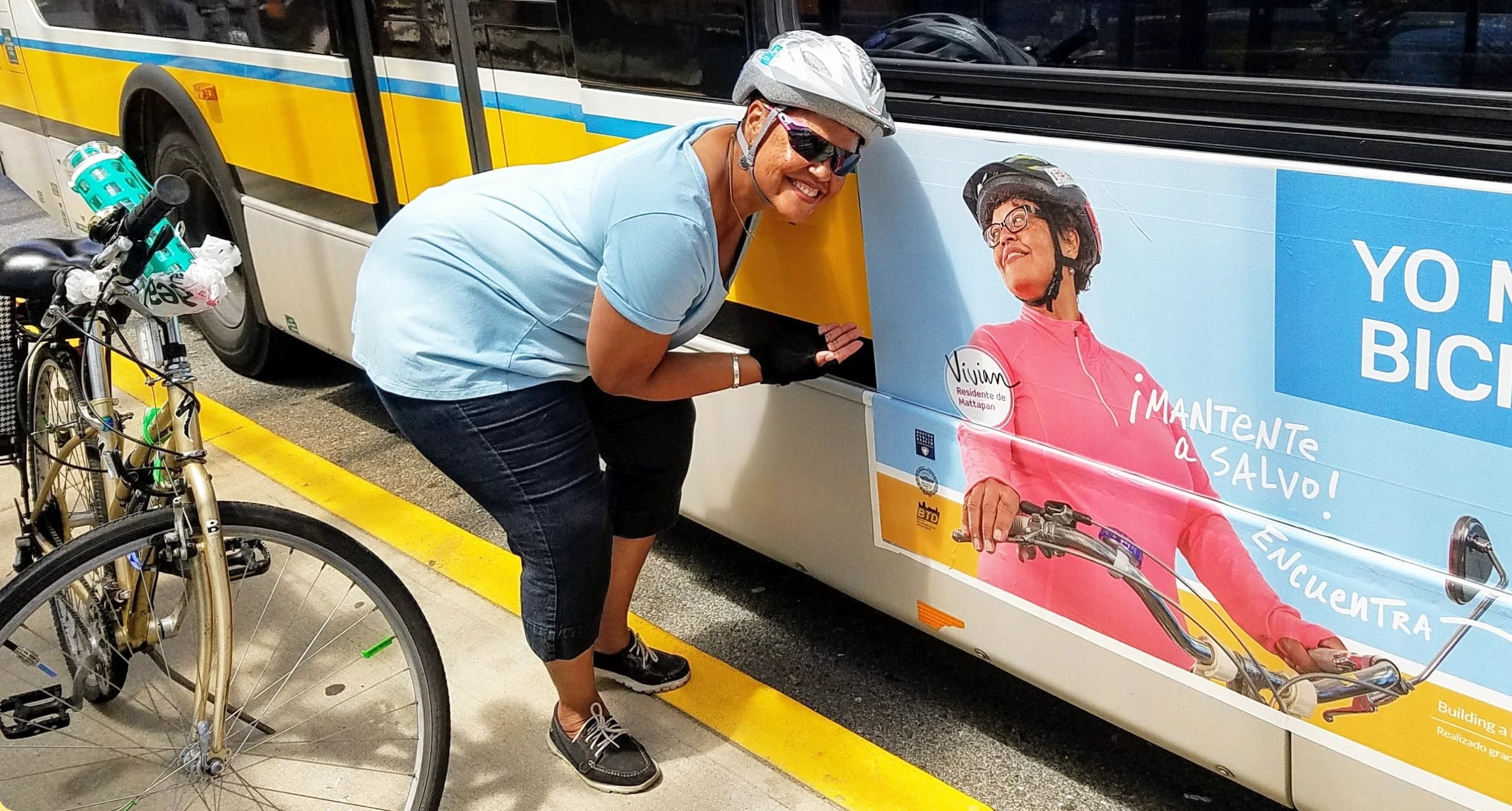 Vivian poses next to a bus displaying a cycling safety poster that features her.