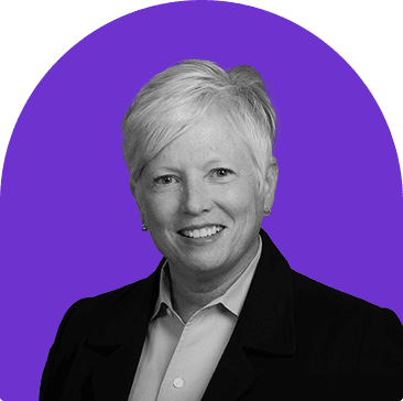 Black and white headshot of Annette Clayton, who is smiling and wears a white collared button up shirt with a suit jacket. She has short white hair. The headshot is on a purple curved rectangle background.