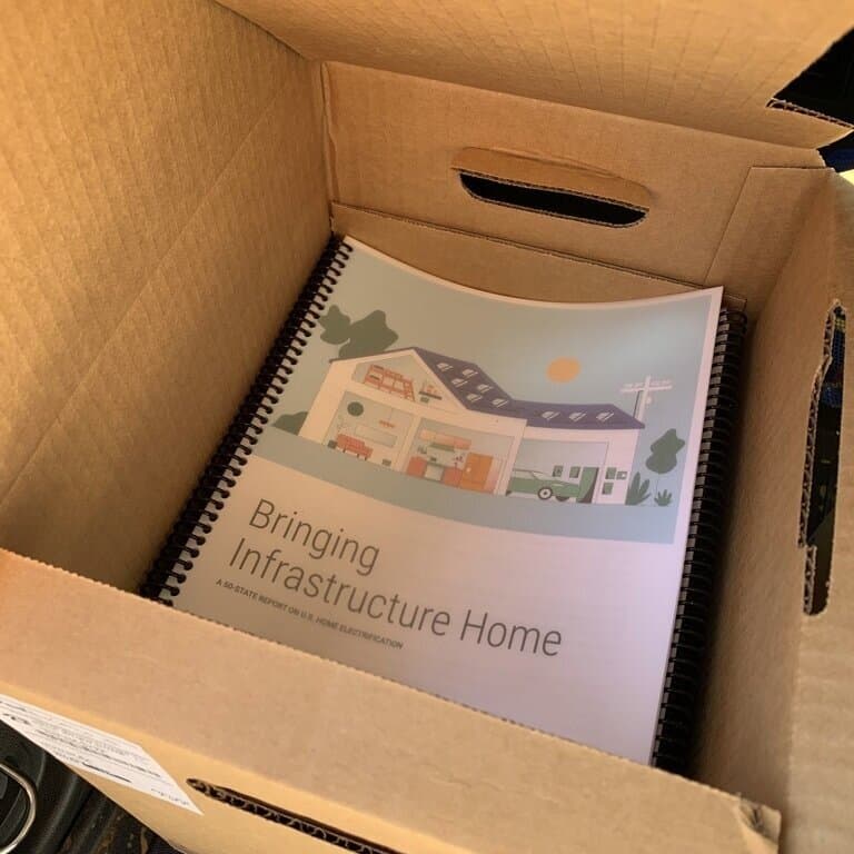 Cardboard boxed filled with a stack of reports, with the front cover text: Bringing infrastructure home
